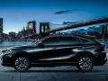 Elegancki, czarny Toyota Harrier lśni nocą na tle rozświetlonego miasta i mostu.