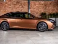 Elegancki, brązowy sedan auto z nowoczesnymi felgami stoi na tle ceglanej ściany.
