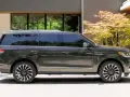 Ciemnoszary Lincoln Navigator SUV zaparkowany przed nowoczesnym domem z drzewem klonu japońskiego.