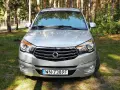 Srebrny SsangYong Rodius z przodu, zaparkowany na tle lasu.