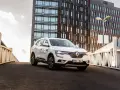Biały Renault Koleos na tle nowoczesnego budynku. Czy warto zainwestować? Sprawdź interrisk opinie.