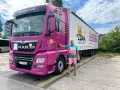 Mężczyzna obok różowej ciężarówki MAN. Na naczepie napis "JA ZDAM SZKOŁA JAZDY". Całkowity koszt prawa jazdy kat C+E jest tu na wyciągnięcie ręki!