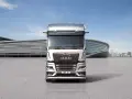 Nowy MAN TGX, lśniący srebrny, przed nowoczesnym budynkiem.