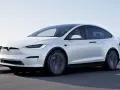 Biała Tesla Model X w ruchu. Zastanawiasz się, ile kosztuje Tesla? Ten luksusowy SUV elektryczny to marzenie wielu kierowców.