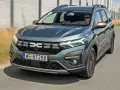 Dacia Jogger w zielonym kolorze jedzie po drodze. Sprawdź atrakcyjną dacia jogger cena i wybierz swój wymarzony samochód.