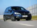 Ciemnoniebieski BMW van na tle jasnego nieba i barier dźwiękochłonnych.