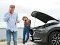Zmartwiona para przy awaryjnym samochodzie. Mężczyzna dzwoni po pomoc, kobieta zrezygnowana. Hestia assistance przyjdzie z ratunkiem.