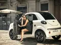 Stylowa kobieta w sukience wysiada z białego samochodu Microcar. Idealny na miejskie wypady, nawet jeśli to Twój pierwszy samochod bez prawka.