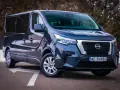 Ciemnoszary Nissan NV300 z nowoczesnymi światłami LED stoi na parkingu.