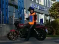 Szczęśliwa kursantka z prawem jazdy kat. A na motocyklu, w kamizelce z literą L, przed budynkiem WORD.