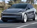Szary Tesla Model Y w ruchu. Sprawdź aktualną tesla model y cena i możliwości tego elektrycznego SUV-a.