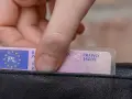 Dłoń wkłada do czarnego portfela polskie prawo jazdy. Widoczny numer blankietu prawa jazdy.