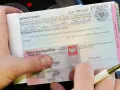 Dłoń trzyma mandat karny i dowód osobisty, obok długopis.