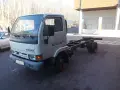 Biały Nissan Cabstar bez zabudowy, z widocznym gołym podwoziem i podwójnymi tylnymi kołami, stoi na kostce brukowej.