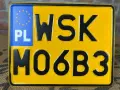 Żółta tablica rejestracyjna z czarnymi znakami "WSK MO6B3" i niebieskim polem "PL" z gwiazdkami UE.