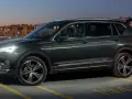 Ciemnozielony SUV z siedmioma miejscami stoi na parkingu nocą, z widokiem na budynki mieszkalne.