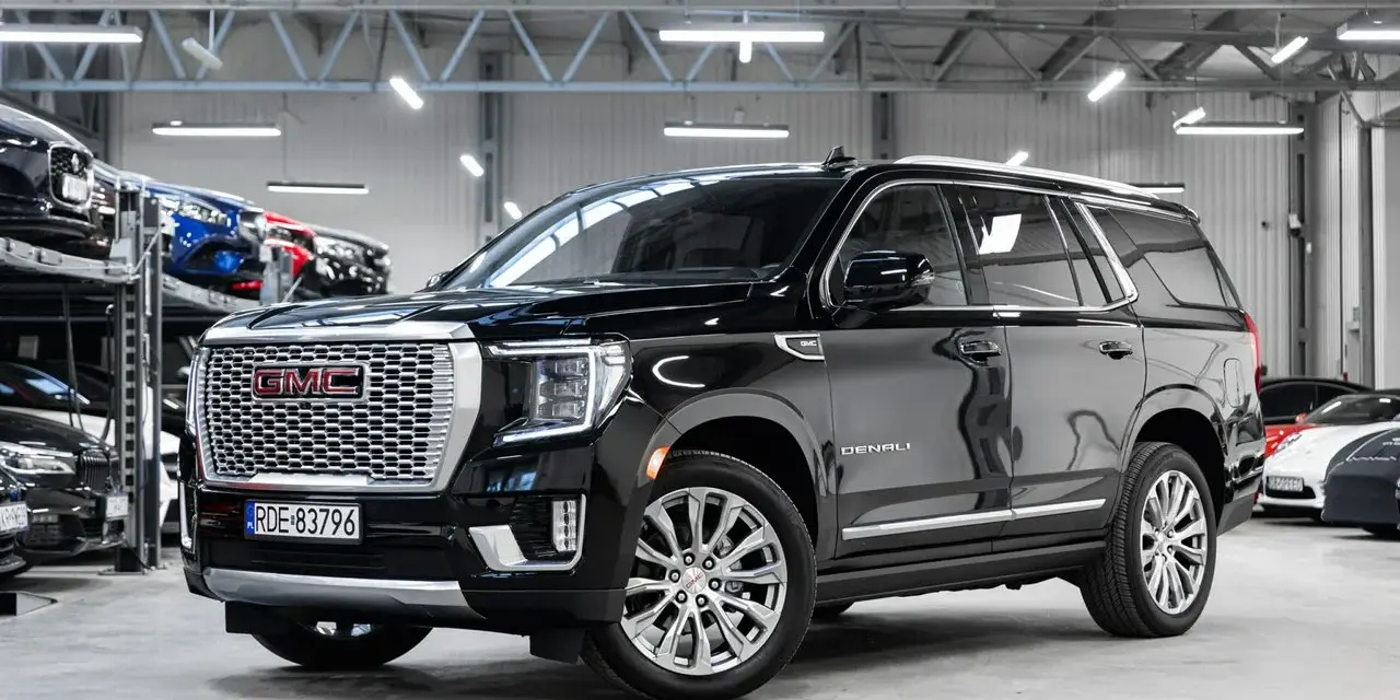 Czarny GMC Yukon Denali lśni w salonie samochodowym, gotowy na przygodę.