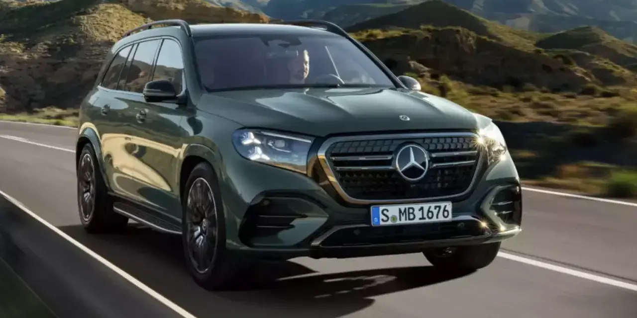 Zielony Mercedes GLS 580 pędzi po krętej drodze wśród gór.