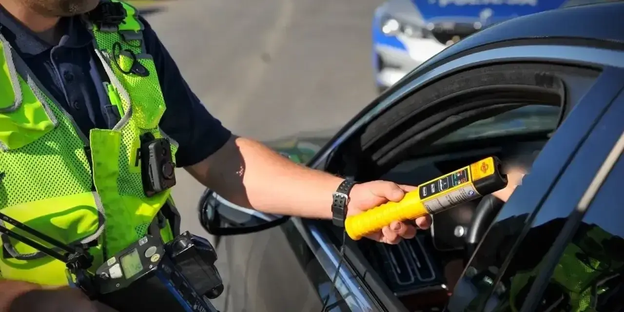 Policjant z Lubuskiej Policji bada kierowcę alkomatem. Za jazdę po alkoholu, nawet 1 promil, prawo jazdy jest zabierane.