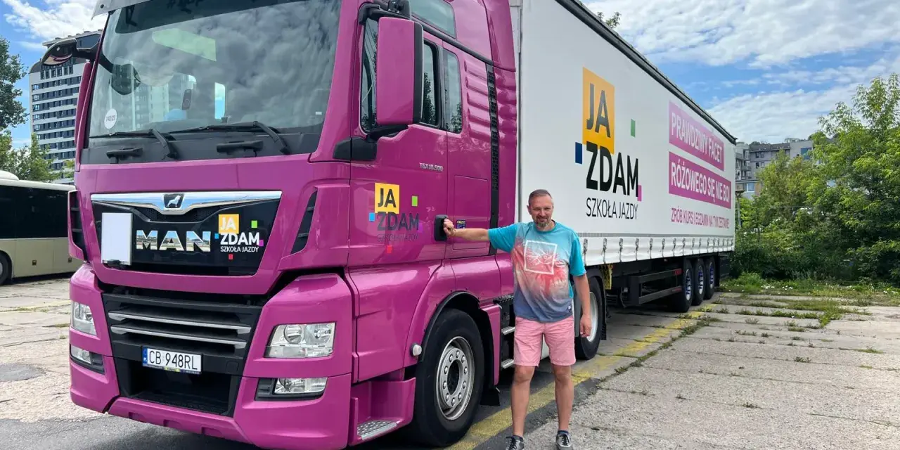 Mężczyzna obok różowej ciężarówki MAN. Na naczepie napis "JA ZDAM SZKOŁA JAZDY". Całkowity koszt prawa jazdy kat C+E jest tu na wyciągnięcie ręki!