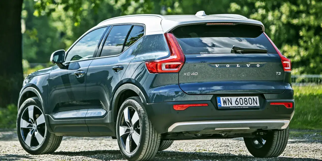 Tylna część ciemnoszarego Volvo XC40 z białym dachem, zaparkowanego na żwirowej drodze. Sprawdź aktualną volvo xc40 cena.