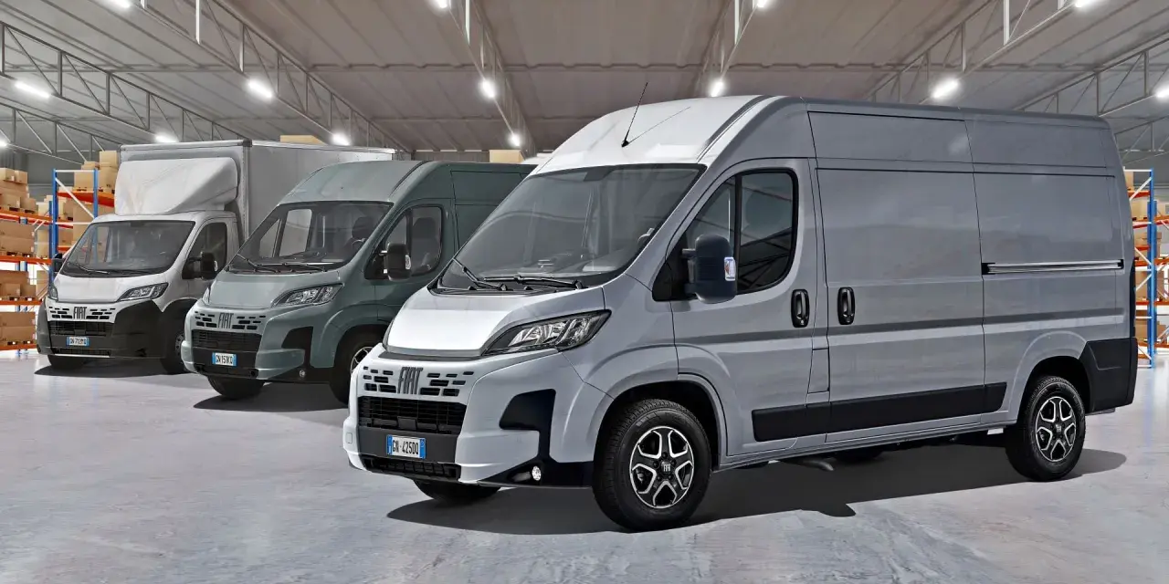Rząd szarych furgonetek Fiat Ducato Maxi w magazynie z półkami i pudełkami.