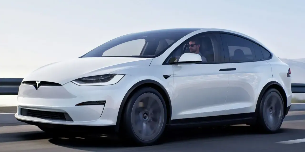 Biała Tesla Model X w ruchu. Zastanawiasz się, ile kosztuje Tesla? Ten luksusowy SUV elektryczny to marzenie wielu kierowców.
