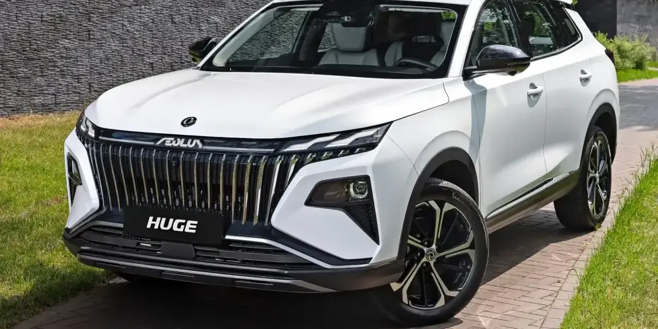 Nowy, biały chinski suv z imponującym grillem i felgami stoi na podjeździe.