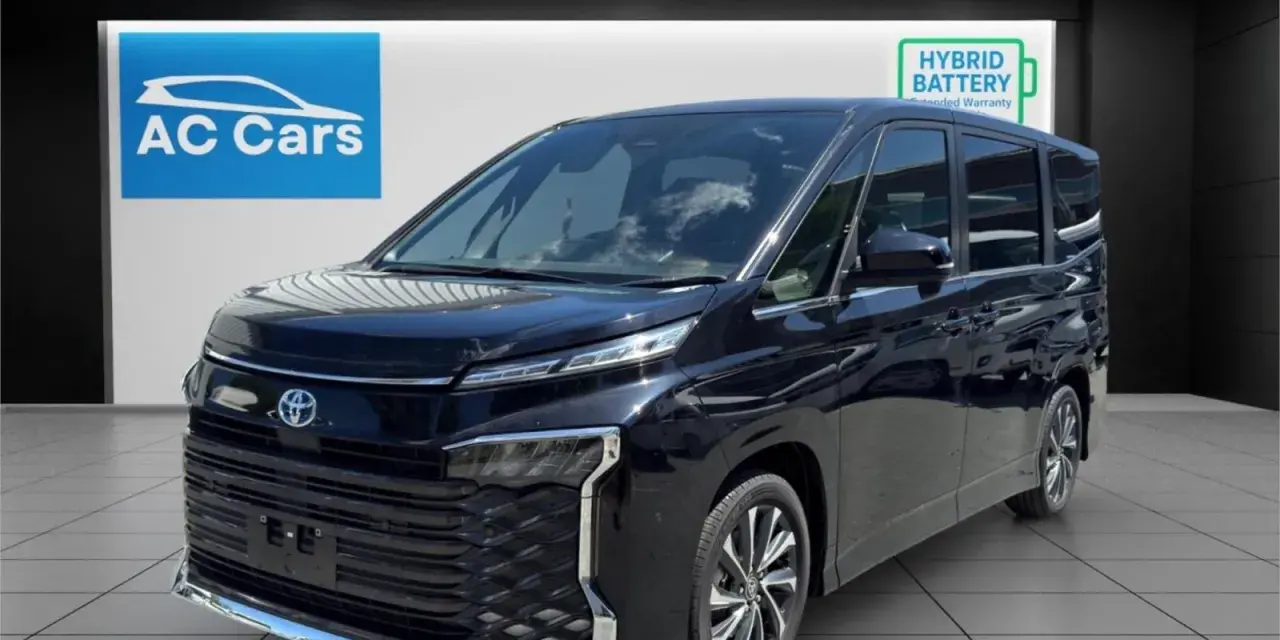 Czarny minivan Toyota Voxy stoi w salonie samochodowym AC Cars.