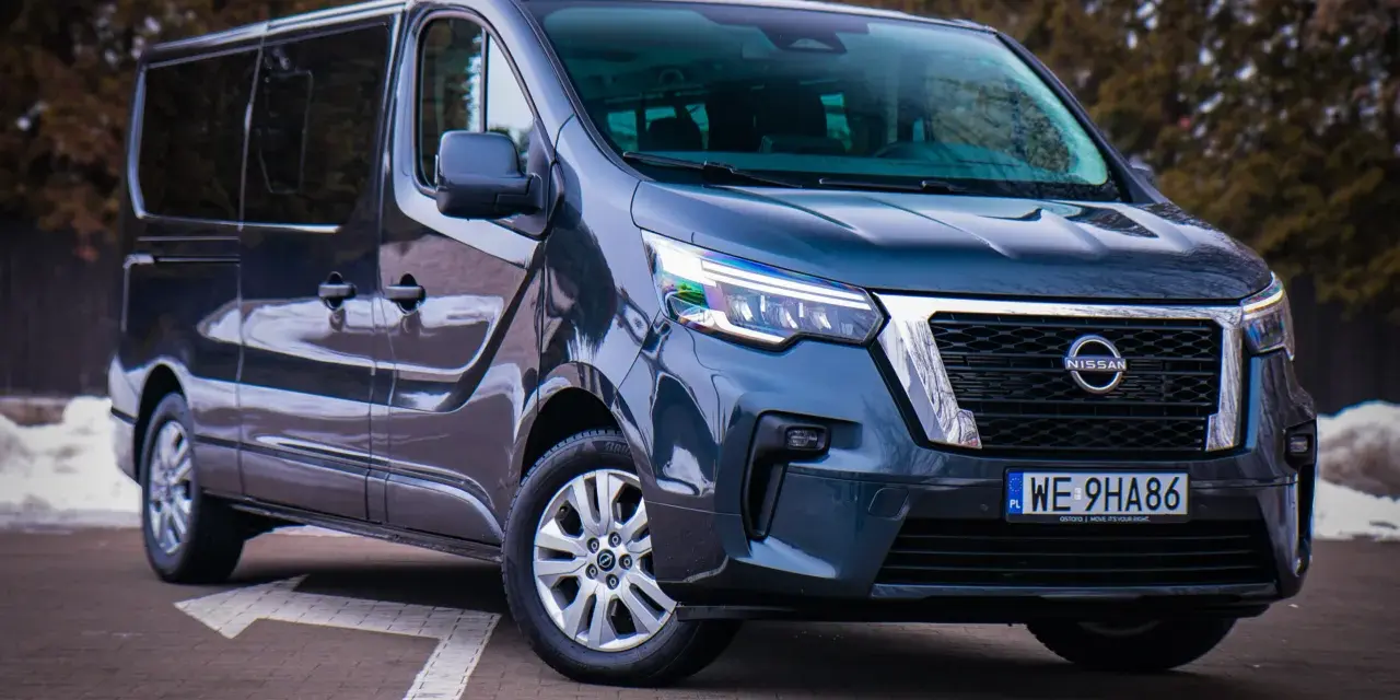 Ciemnoszary Nissan NV300 z nowoczesnymi światłami LED stoi na parkingu.
