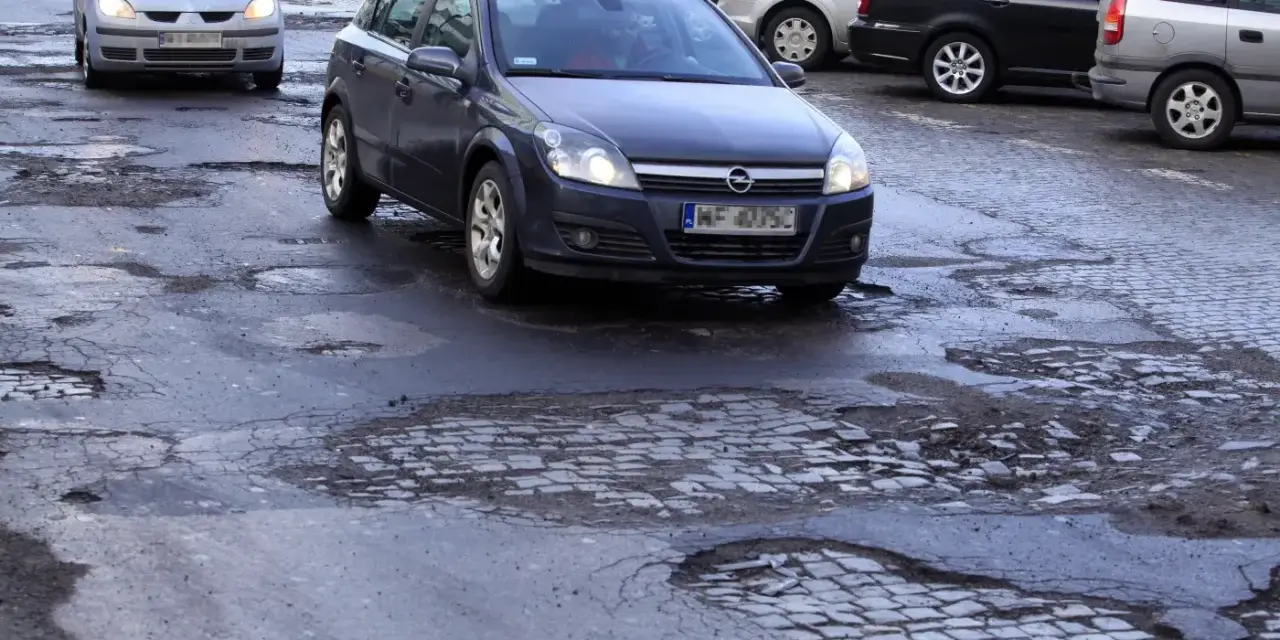 Samochody jadą po dziurawej drodze. Czy warto wykupić ubezpieczenie Europa Ubezpieczenia opinie?