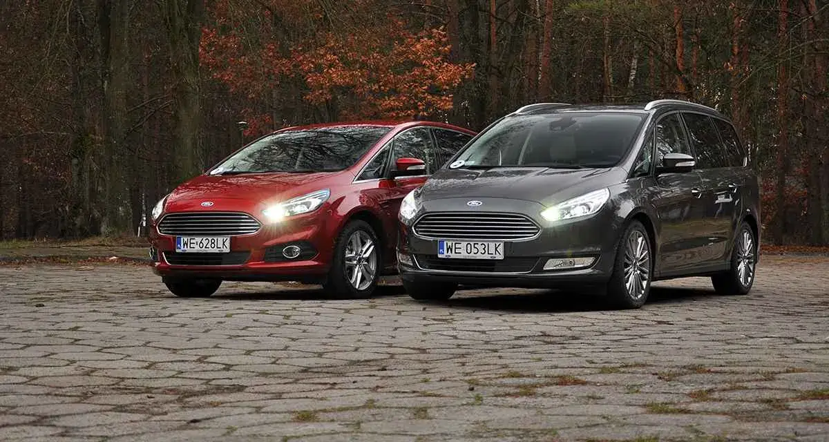Dwa samochody Ford, czerwony S-Max i szary Galaxy, stoją na brukowanej nawierzchni w jesiennym lesie.