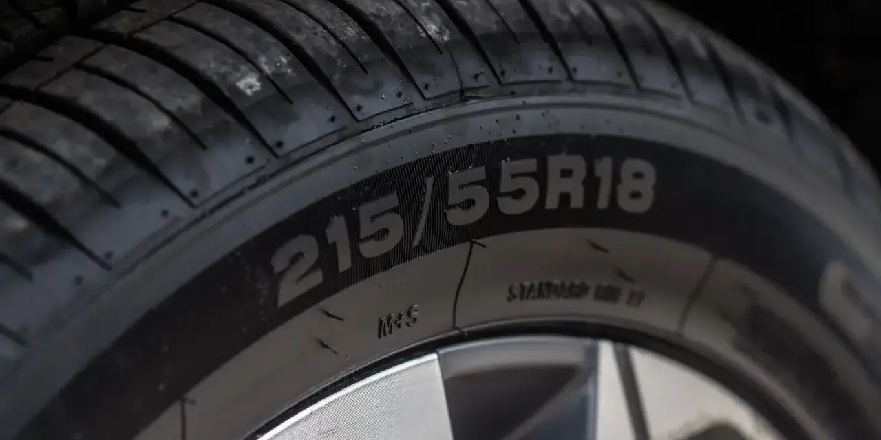 Zbliżenie na bieżnik opony z widocznym oznaczeniem 215/55R18.