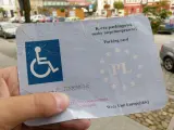 Karta parkingowa dla niepełnosprawnych, z symbolem wózka inwalidzkiego i gwiazdkami UE. Ułatwia parkowanie w mieście.