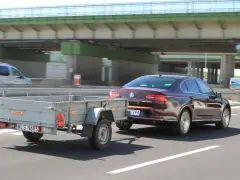 Samochód osobowy ciągnie małą przyczepę, idealną do przewozu bagażu. To przykład, jaka przyczepa na kat B jest praktyczna.