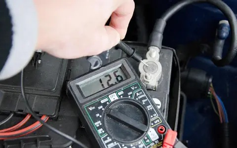Sprawdzanie, jak sprawdzić czy akumulator jest dobry, za pomocą multimetru pokazującego 12.6V.
