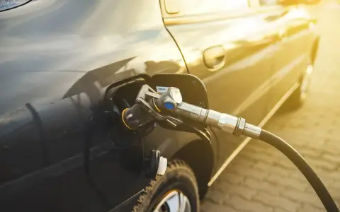 Tankowanie auta. Zastanawiasz się, ile kosztuje gaz do auta? Słońce odbija się od karoserii podczas tankowania.