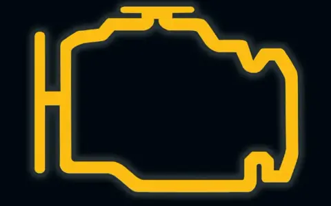 Żółty, migający symbol silnika na ciemnym tle. Czas na wizytę u mechanika, bo to znak, że coś jest nie tak z autem.
