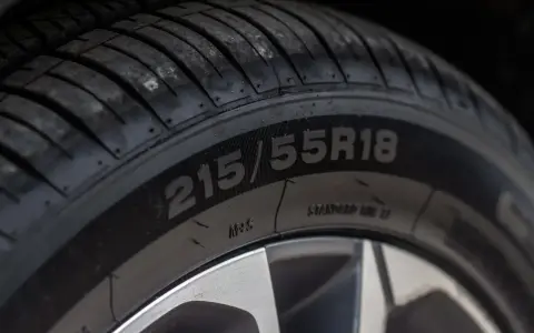 Zbliżenie na bieżnik opony z widocznym oznaczeniem 215/55R18.