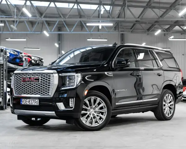 Czarny GMC Yukon Denali lśni w salonie samochodowym, gotowy na przygodę.