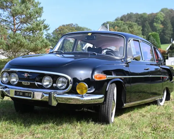 Czarna Tatra 603 lśni na trawie, gotowa na przejażdżkę.