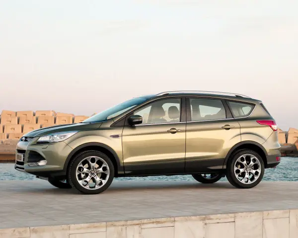 Złoty SUV Ford Kuga stoi na nabrzeżu przy morzu.