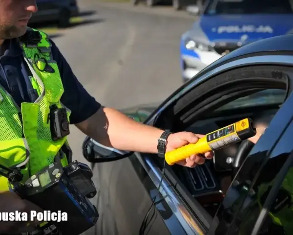 Policjant z Lubuskiej Policji bada kierowcę alkomatem. Za jazdę po alkoholu, nawet 1 promil, prawo jazdy jest zabierane.