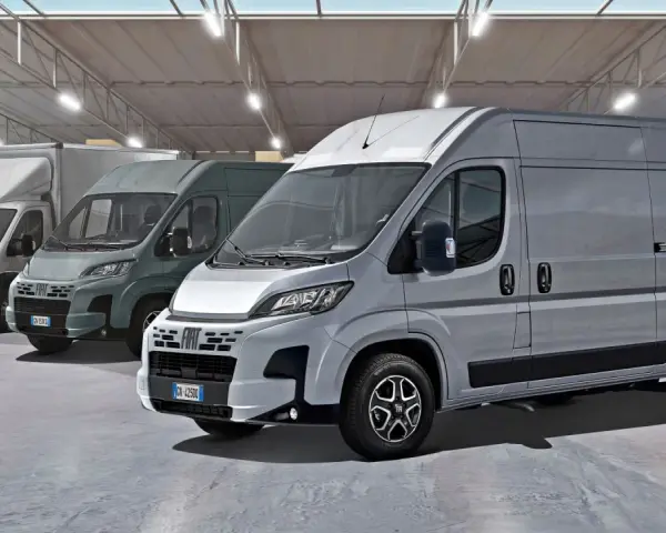 Rząd szarych furgonetek Fiat Ducato Maxi w magazynie z półkami i pudełkami.