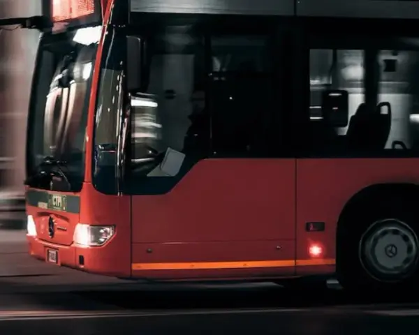 Czerwony autobus w ruchu miejskim, widok z przodu i z boku.