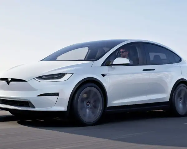 Biała Tesla Model X w ruchu. Zastanawiasz się, ile kosztuje Tesla? Ten luksusowy SUV elektryczny to marzenie wielu kierowców.