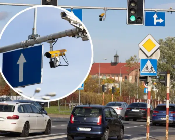 Widok na skrzyżowanie z sygnalizacją świetlną i znakami drogowymi. W powiększeniu widać kamery rejestrujące przejazd na czerwonym świetle.