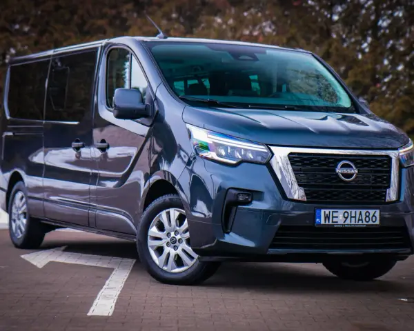 Ciemnoszary Nissan NV300 z nowoczesnymi światłami LED stoi na parkingu.