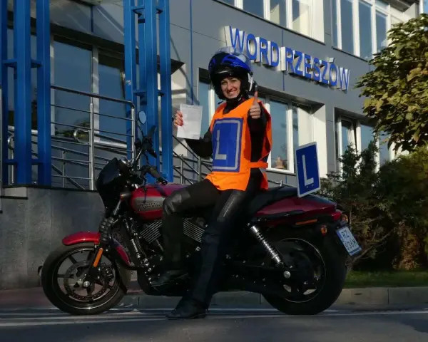 Szczęśliwa kursantka z prawem jazdy kat. A na motocyklu, w kamizelce z literą L, przed budynkiem WORD.