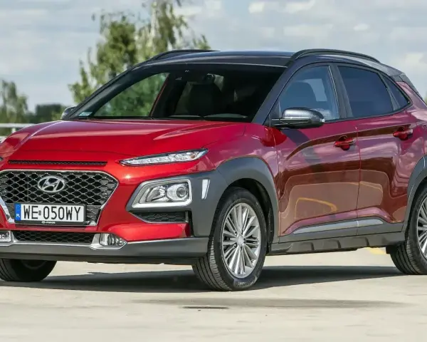 Czerwony, mały SUV Hyundai Kona z czarnym dachem, zaparkowany na zewnątrz.